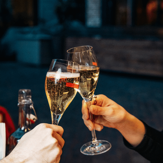 Two champagne glasses touching at Daffodil Mulligan restaurant in Shoreditch, London