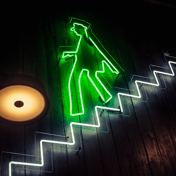Light up sign of a man walking down the stairs at Gibney's bar in Shoreditch