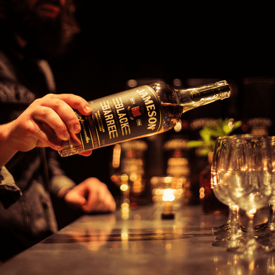Hand pouring whiskey into glasses at Gibney's bar in Shoreditch