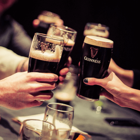 People cheering with Guinness’s at Gibney's bar in Shoreditch